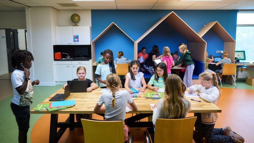 Verschillende kinderen tussen de 7 en 10 jaar spelen en kleuren aan een grote tafel